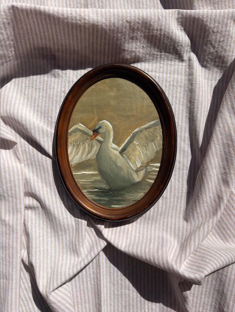 Small oval painting of a swan on a textured fabric background