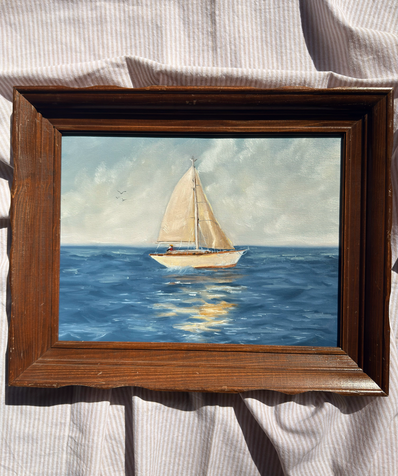 Framed painting of a sailboat on water with a wooden frame.