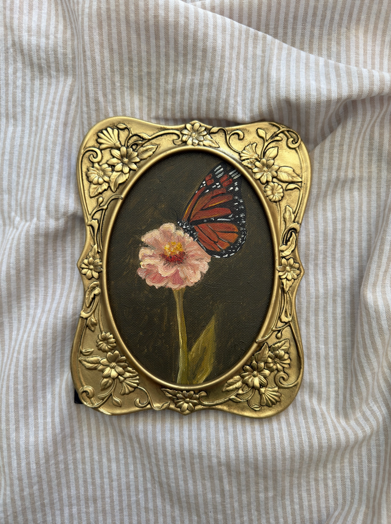 Gold frame with butterfly and flower design on a striped fabric background