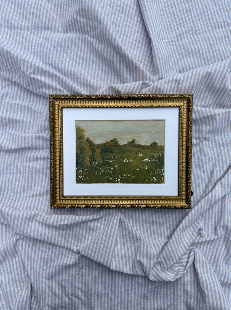 Framed painting of a landscape on a textured blue fabric background