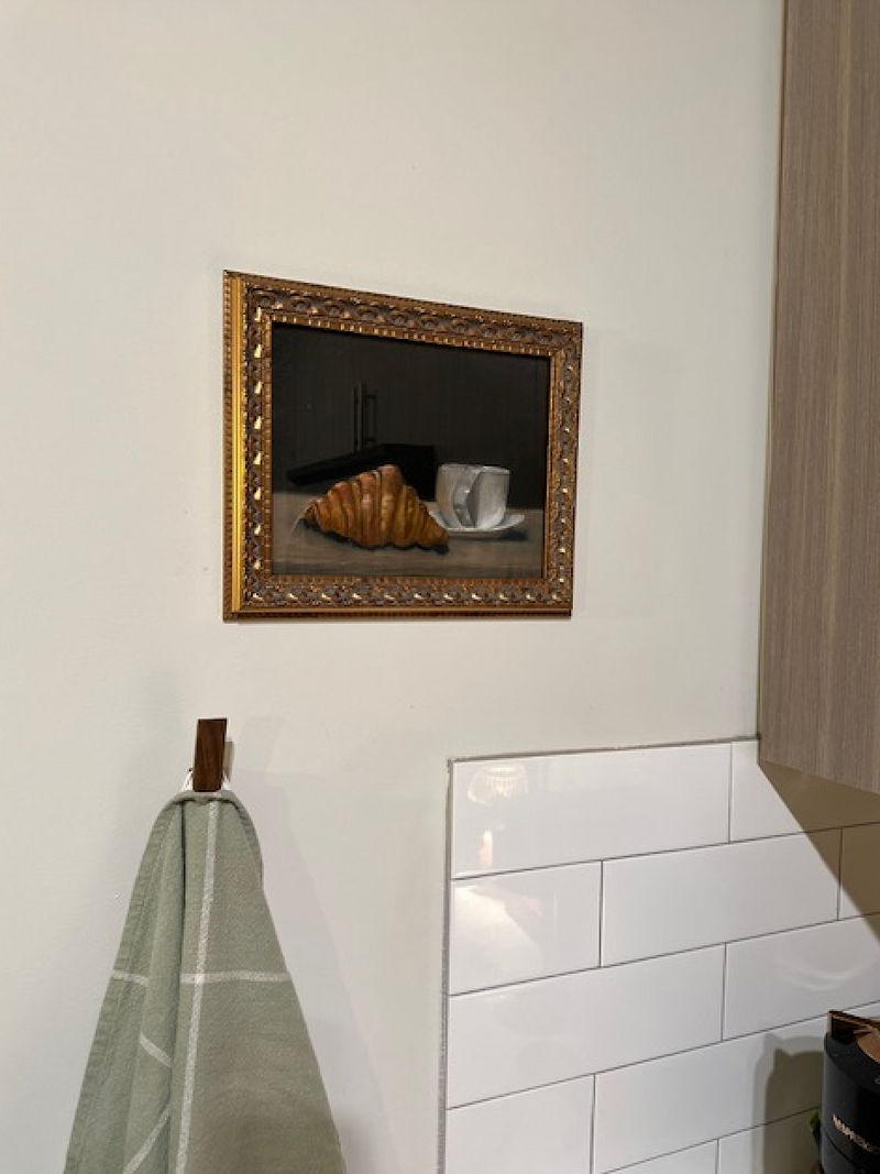 Framed mirror on a wall above a white tiled bathroom cabinet.