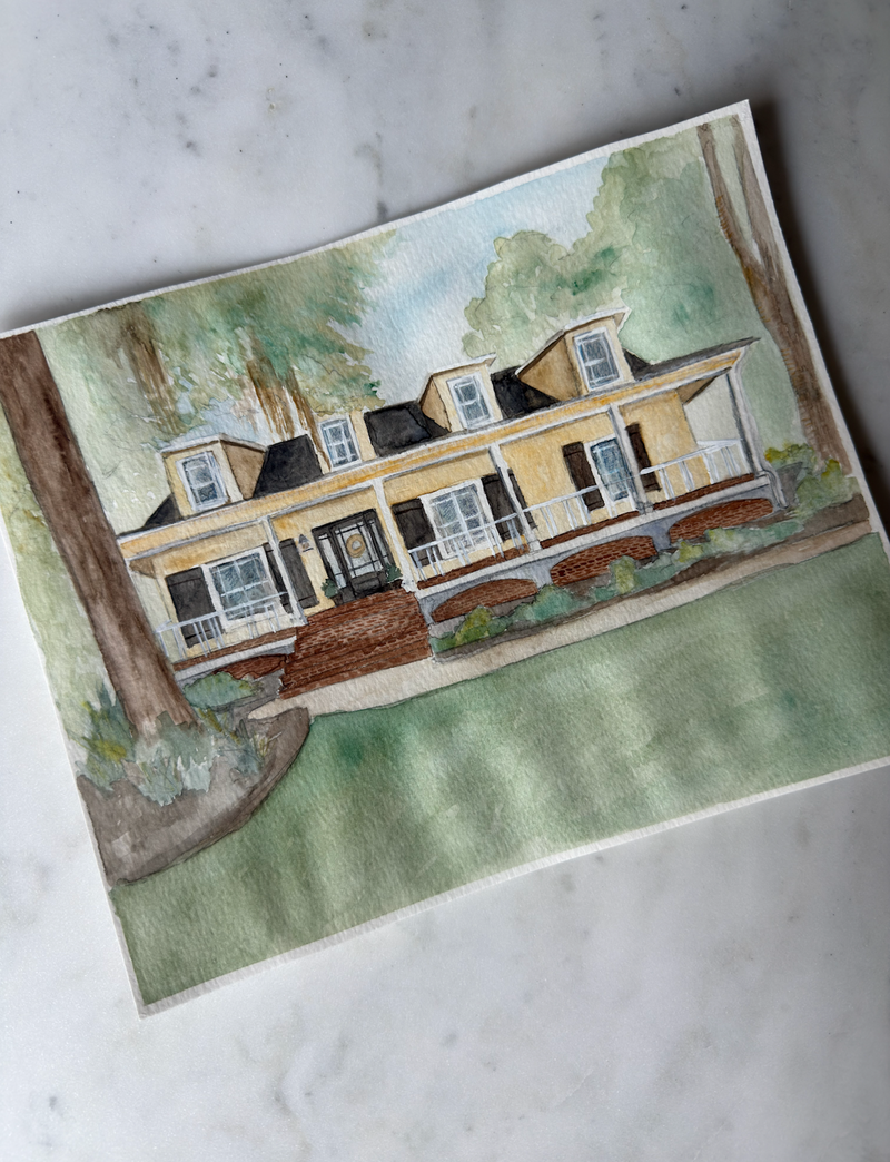Painting of a two-story house with a tree in front on a marble surface